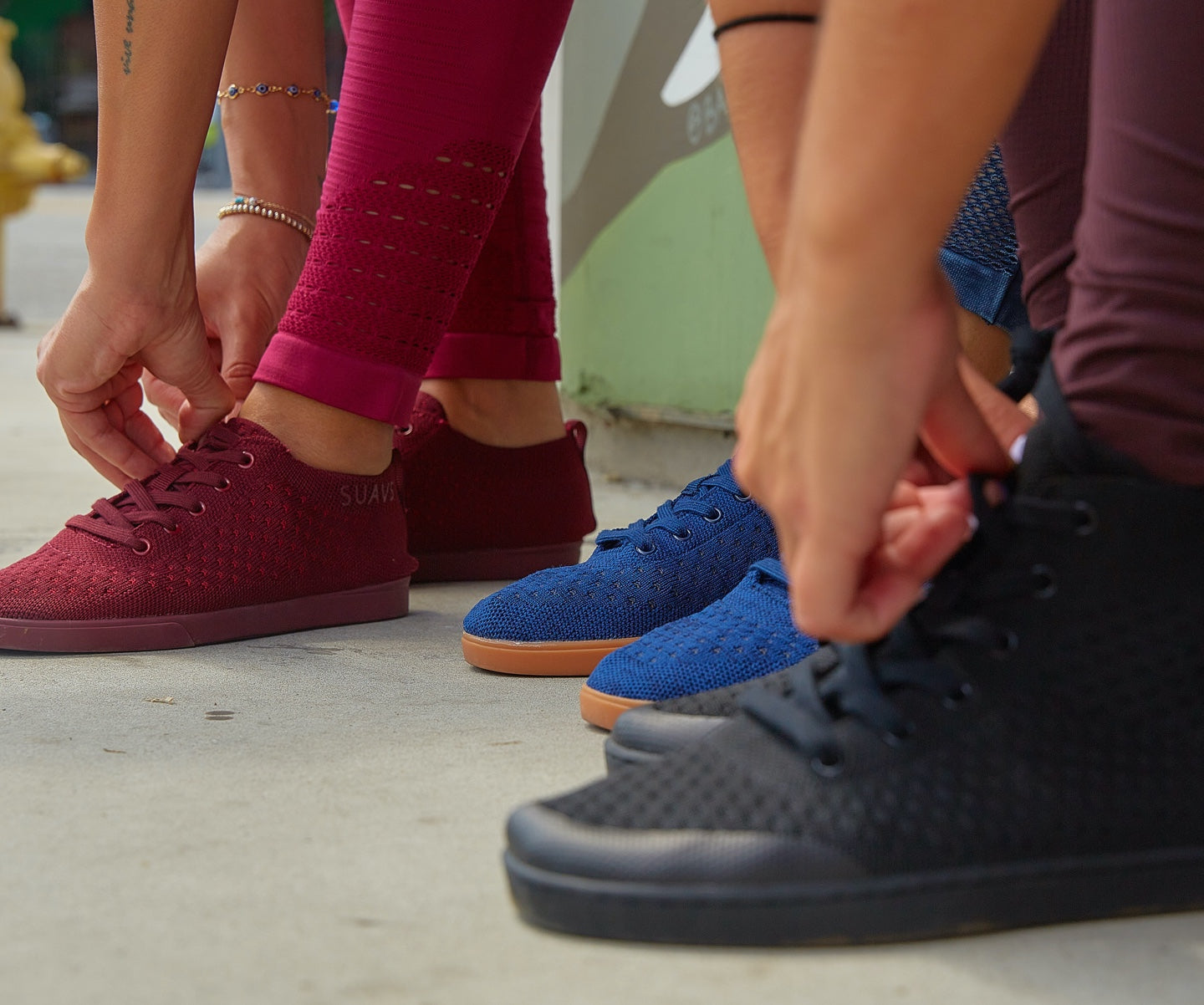 Group of people reaching down to tie their SUAVS shoes.